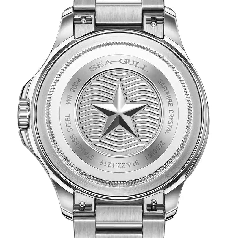 Silver stainless steel women's watch with a metal link bracelet, shown from the back. The round case features an engraved star and wave design in the center, with 'SEA-GUILL' and 'STAINLESS STEEL' engraved on the back.
