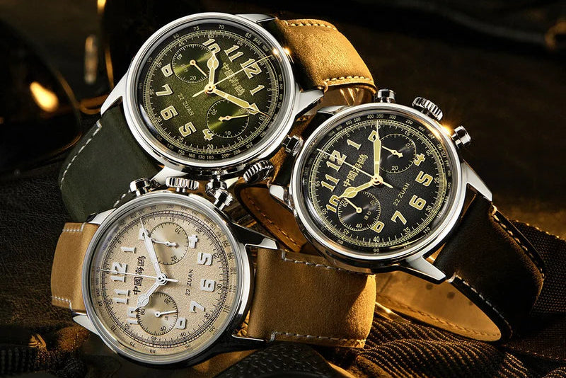 Three vintage-style watches with leather straps on a textured surface.
