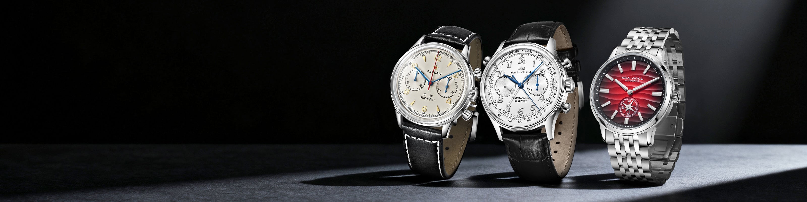 Three watches displayed on a dark surface with a spotlight effect.