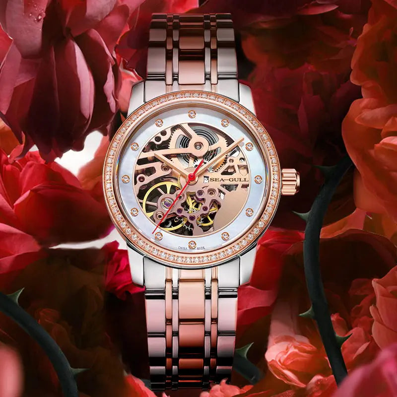 Elegant skeleton watch with rose gold accents and diamond bezel, set against red roses