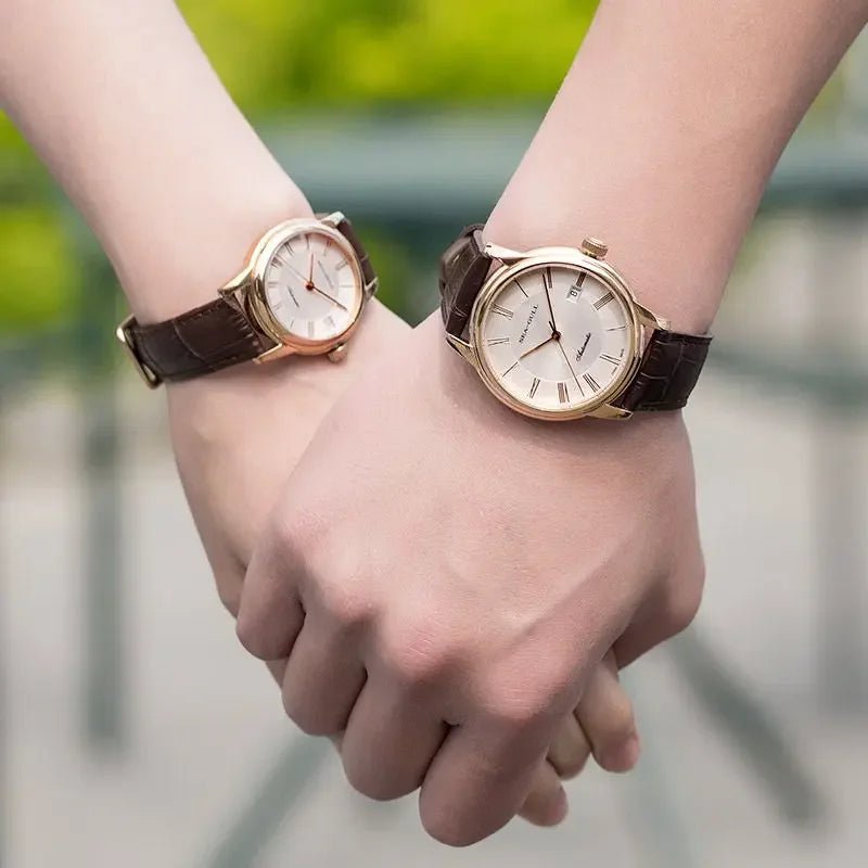 Paar mit passenden goldfarbenen Armbanduhren mit braunen Lederarmbändern, das draußen Händchen hält